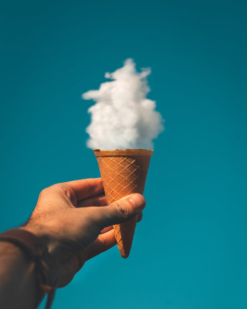 man holding ice cream cone under cloud